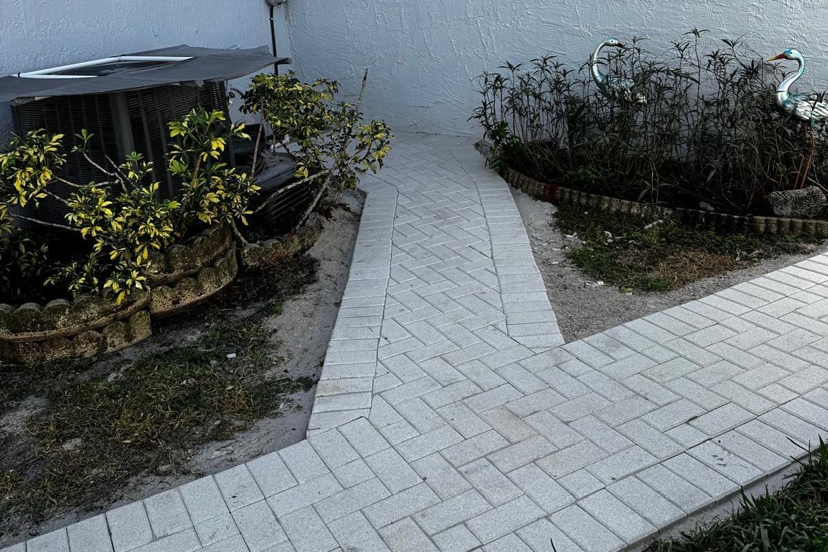 Finished paver walkway installation running alongside a white wall at a Wellington, FL home